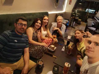 Six guests of the evening at a table on the bar's green sofa, with cocktails, a dessert and big smiles