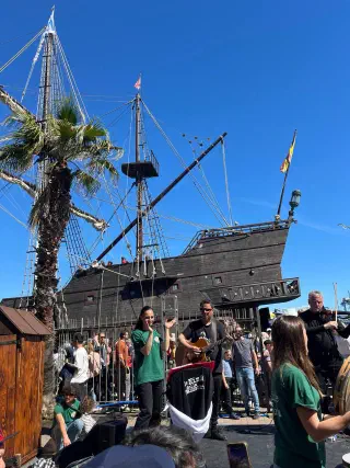 Dark wooden galleon moored on the Sète quay, musicians playing in front of a festival crowd