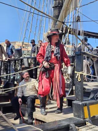 Actor in a red pirate costume with a hook for a hand on the deck of a historic tall ship in Sète