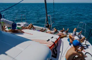 People sunbathe on the catamaran's trampoline net, an inflatable platform beside them