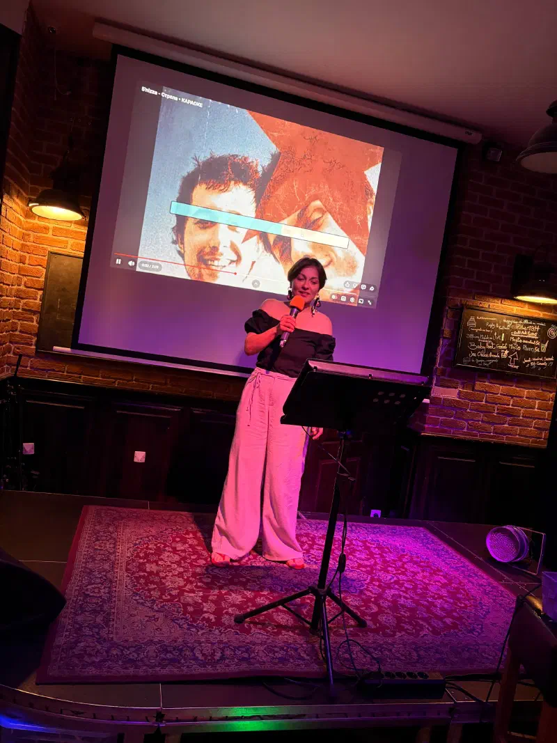 Evening karaoke: a singer with a microphone on stage in front of the lyrics screen