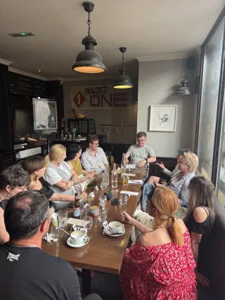 Players around a long table with numbered cards — the afternoon Mafia game in the pub room