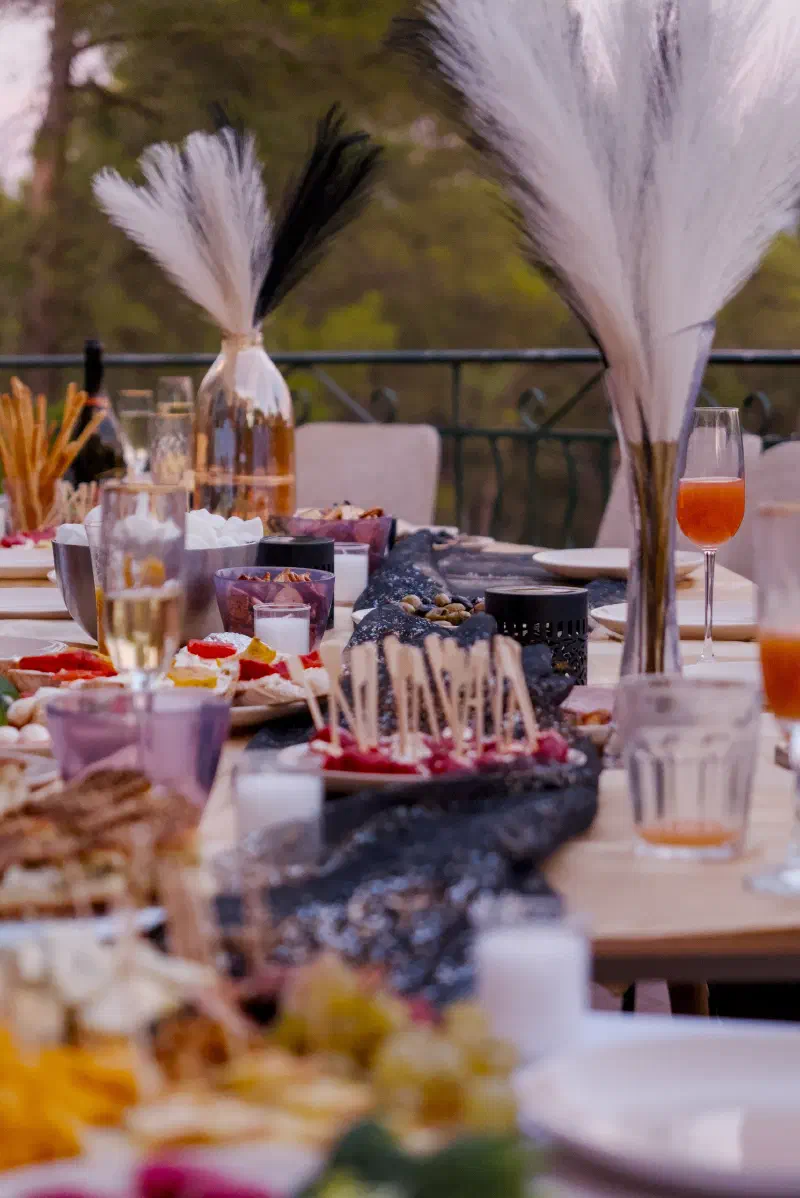 The terrace table set before the guests arrive: black glitter runner, candles, canapés on skewers, pampas grass