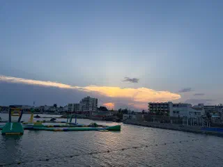 Sunset over the water at Carnon: an inflatable aqua park near the shore and seafront buildings in evening light
