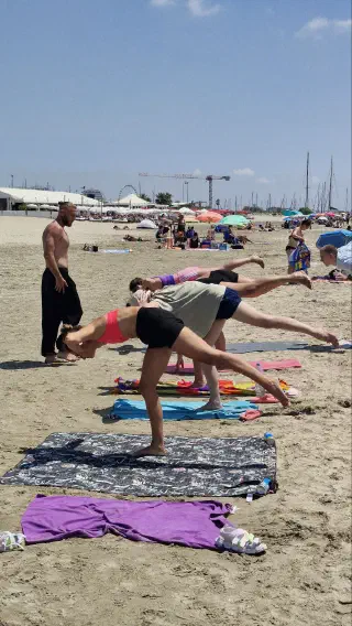 Yoga practice on mats — one-leg balance poses; yacht masts and a Ferris wheel in the distance