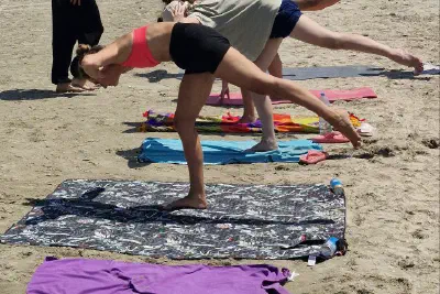 Yoga practice on mats — one-leg balance poses; yacht masts and a Ferris wheel in the distance