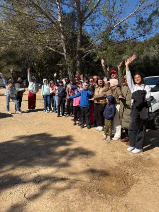 Hiking group waving at a gravel car park under pine trees before setting off on the trail