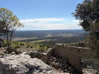 View from the castle ruins: a stone wall with an arch and the plain stretching to the sea on the horizon