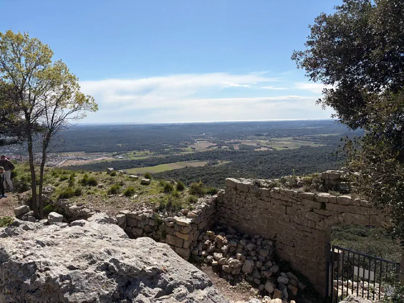 View from the castle ruins: a stone wall with an arch and the plain stretching to the sea on the horizon