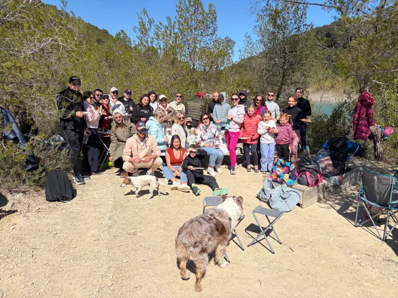 Group photo of the hike: about forty people with kids and dogs in a clearing by Lac de Cécélès