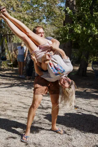 A guest lifts his dance partner in a hold, trees in the background