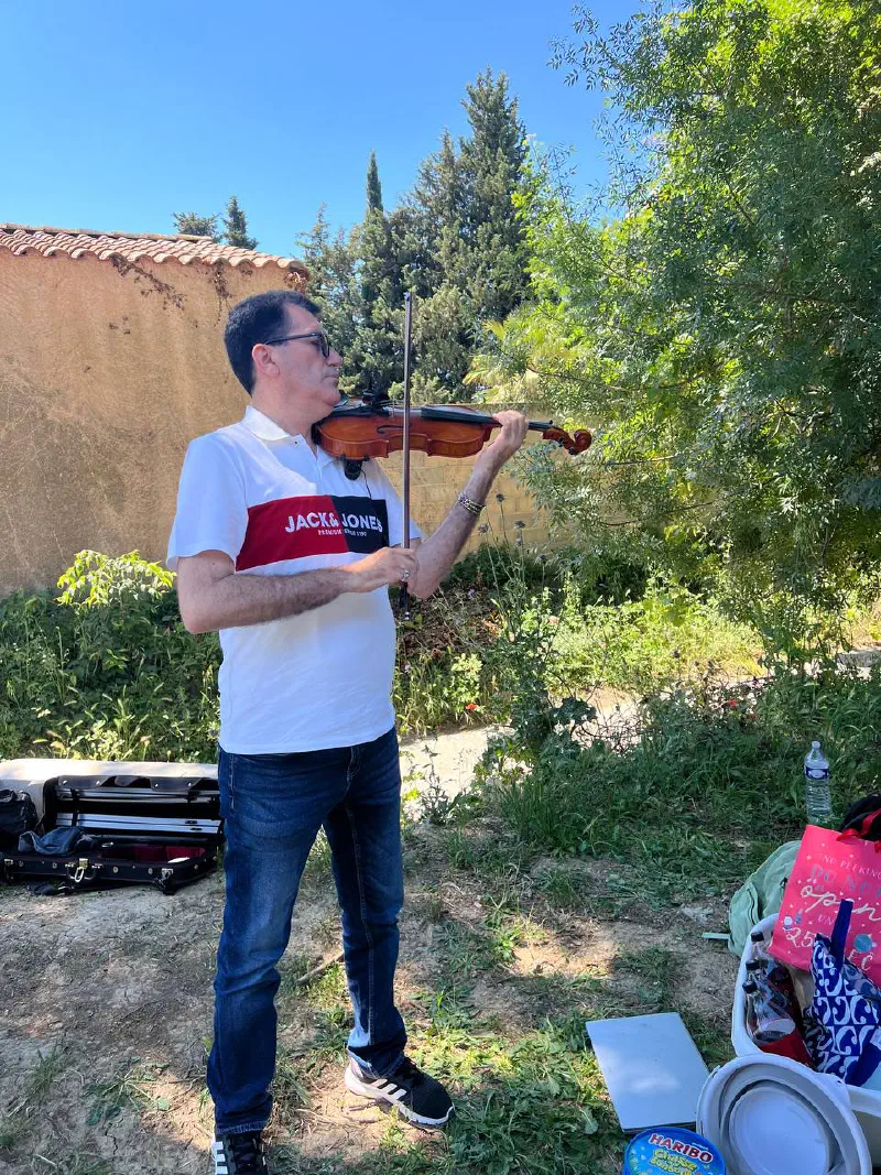 Violinist playing in the shade of the trees beside the grounds