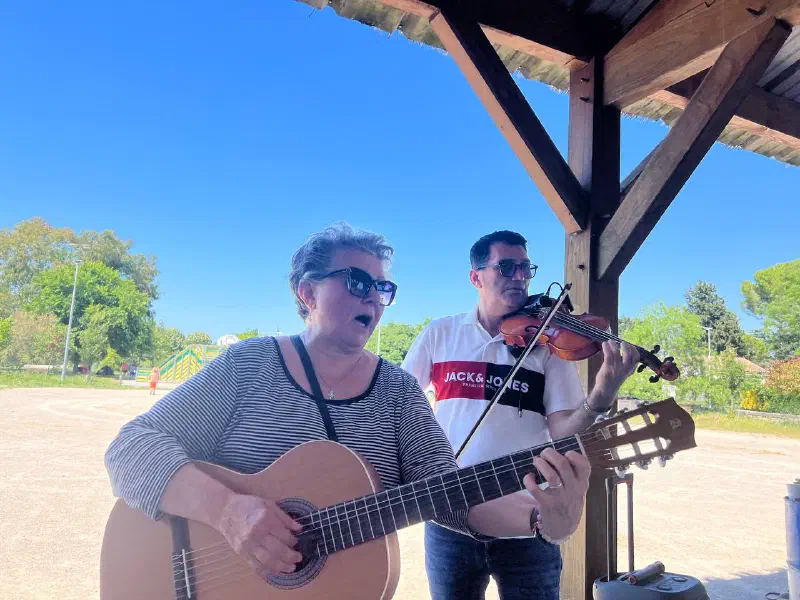 Live music under the shelter: a woman sings with a guitar, a violinist plays along