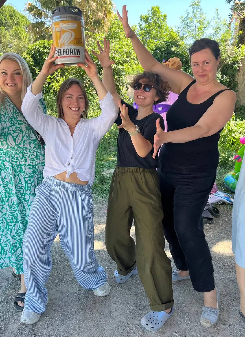 Four women strike a playful pose lifting a small keg overhead