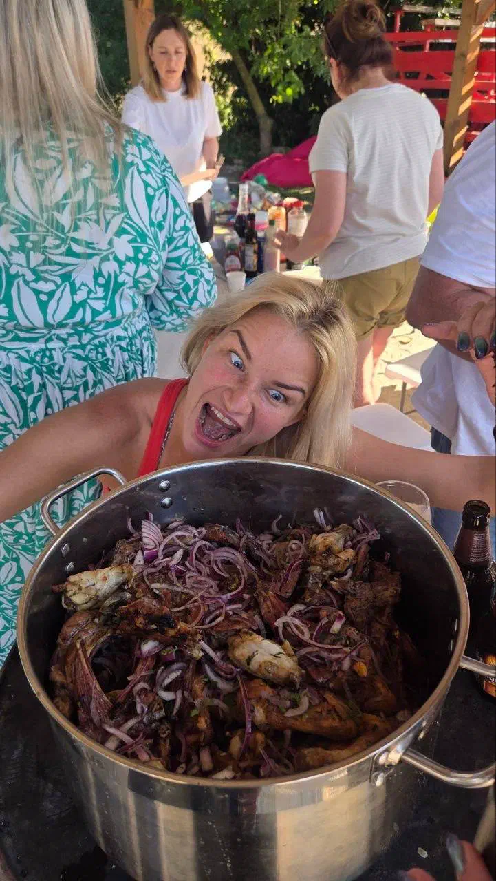 Huge pot of grilled meat with red onion and a delighted guest posing behind it