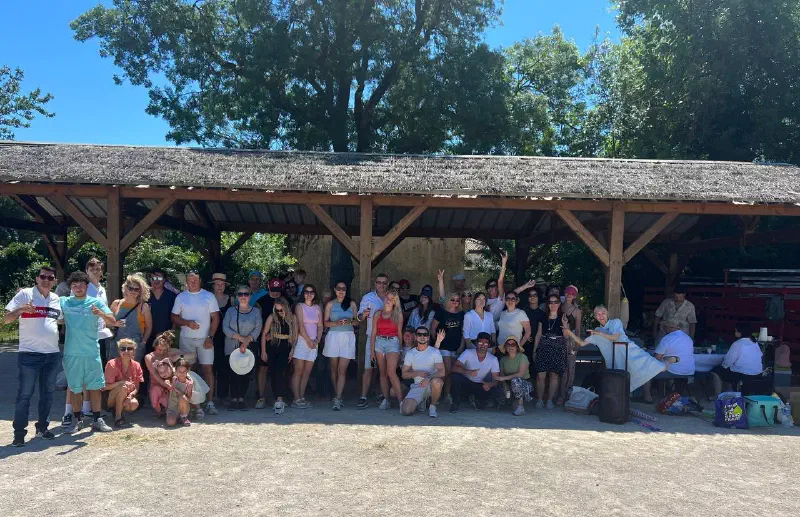 Group photo: dozens of adults and children under the wooden shelter in the park