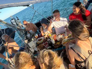 The group around a table of snacks and drinks in the yacht's cockpit, open sea all around